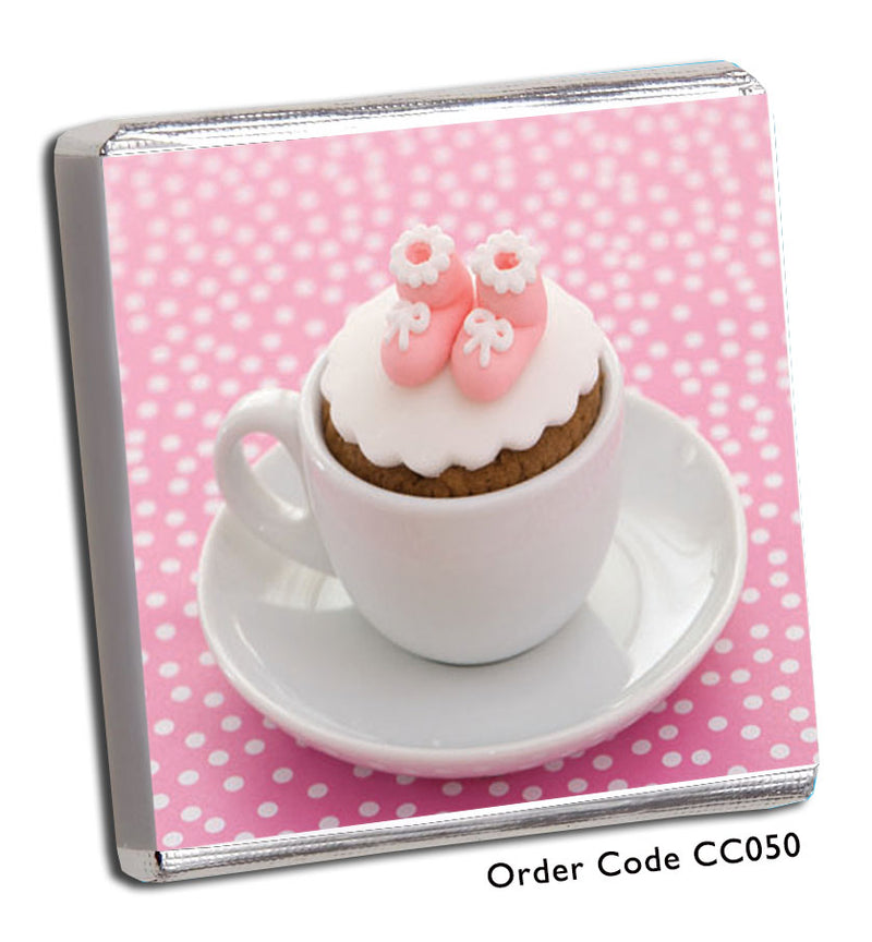 cup and saucer with mini cake inside with pink booties on top